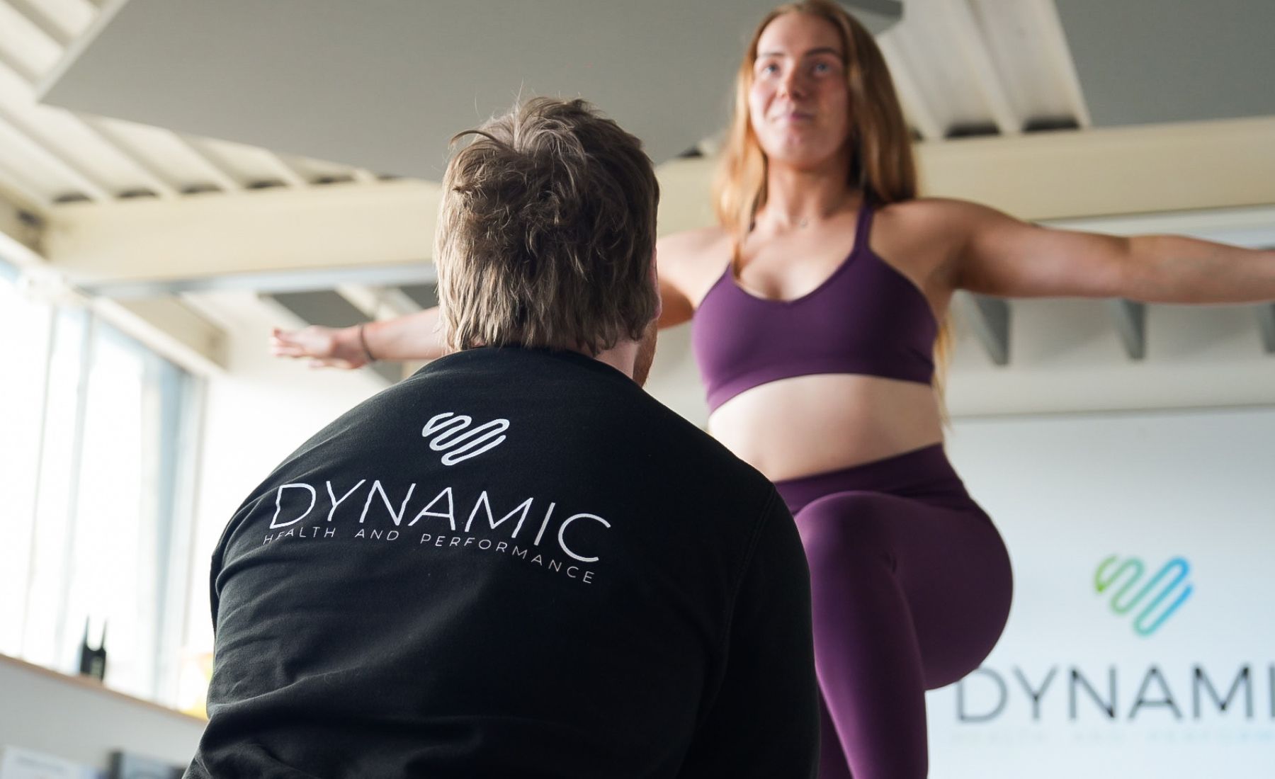 A person balances on one leg during a fitness session with a trainer from Dynamic.