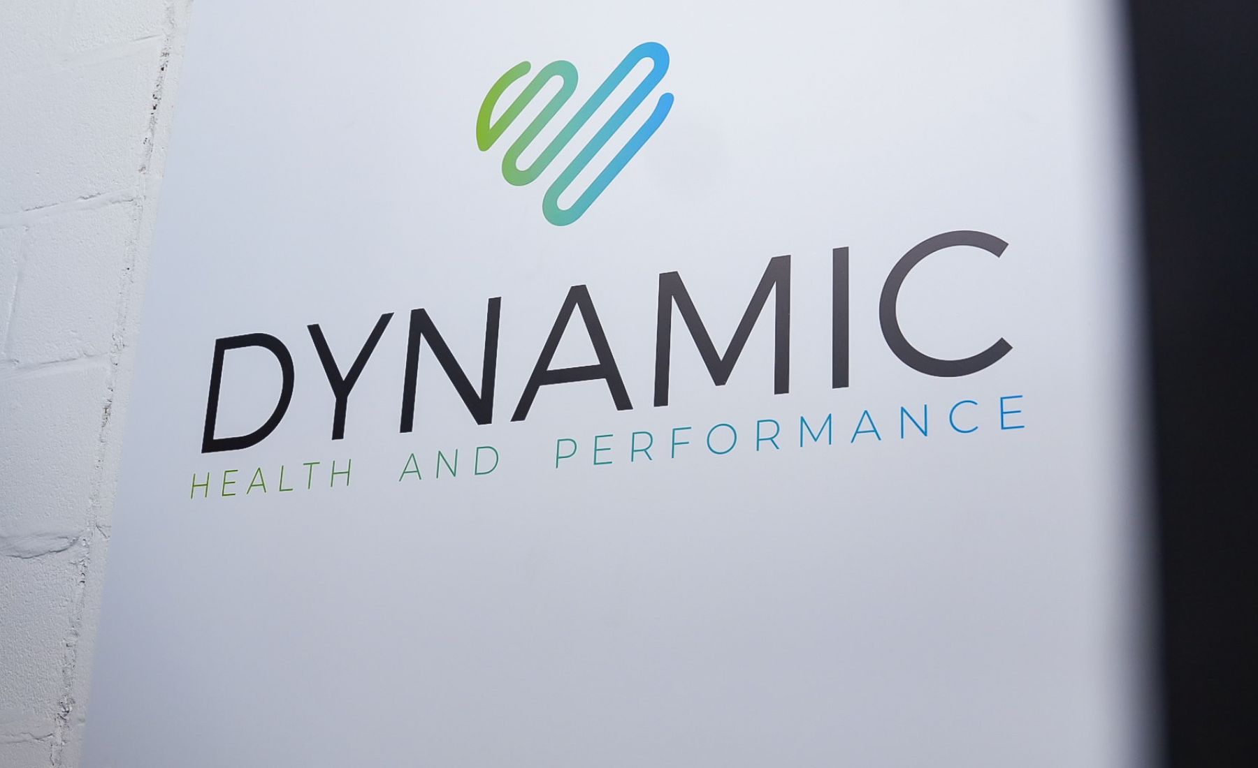 Sign displaying the text "Dynamic Health and Performance" with a stylized logo above.